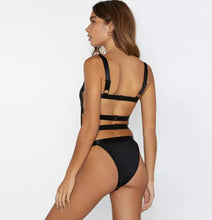 Load image into Gallery viewer, Bad Gyal Riri Bodysuit- Black We're bringing you the ultimate sheer mesh cut out bodysuit! Perfect for building your favorite looks all year round. This bodysuit comes in a luxurious sheer fabric with satin ribbon straps featuring a plunging square neckline sexy cut out back and snap seat closure. Made of materials that allow great stretch and breathable fabric. Style it with a blazer and jeans or one of our sexy pleated skirts matching high waist legging and heels to create a casual-chic look.