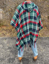 Load image into Gallery viewer, Drape yourself in style and warmth with our pretty Giving You Everything poncho featuring warm material plaid patterned with a roomy hood, open sides, and an ultra-draped silhouette that falls into an uneven knee-length hemline with fringe trim detailing!