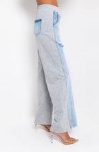 Load image into Gallery viewer, In The Mix Denim Sweatpants. These bottoms are made from a mix of heather grey cotton sweat and light wash denim fabrication. These pants feature distressed rips at the knees, straight leg pants, an elastic waistband, two front and back pockets, and a button detail. Style these with a cropped hoodie and a pair of white sneakers!