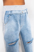 Load image into Gallery viewer, In The Mix Denim Sweatpants. These bottoms are made from a mix of heather grey cotton sweat and light wash denim fabrication. These pants feature distressed rips at the knees, straight leg pants, an elastic waistband, two front and back pockets, and a button detail. Style these with a cropped hoodie and a pair of white sneakers!