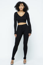 Load image into Gallery viewer, This Just Chill Set is every wardrobe essential. Featuring a black rib kitted fabric with a V neckline top with long sleeves, high rise pants with soft elasticized waistband, lightweight material. Style with a high heel or boots and handbag for a weekend look you'll love!