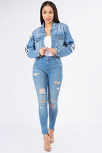 Load image into Gallery viewer, Update your denim collection with our cropped jacket we are obsessing over. Featuring a mid wash denim material with a raw edge and a cropped length, double up your denim with our matching mid-wash jeans and a nude crop top for a combo that can be dressed up or down.