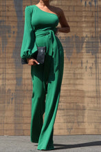 Load image into Gallery viewer, One Shoulder Jumpsuit - Dark Green This jumpsuit is a statement in itself! Perfect for all of your summer fun! This green jumpsuit comes in a wide pant leg featuring a long sleeve one shoulder, adjustable tie belt, and side zipper. Pair this with a stylish heel and handbag for a complete look.