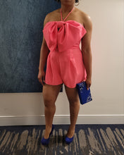 Load image into Gallery viewer, Be sure to stand out in sweeter than ever romper wherever you go from day to night in style! Featuring shapes, a strapless neckline, halter necktie, elastic at the back and a cut out front, textured woven fabric and princess bow. Totally on-trend, tie-front detail accents this chic romper perfectly while pleated shorts complete the look! Hidden back zipper/clasp.