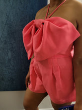 Load image into Gallery viewer, Be sure to stand out in sweeter than ever romper wherever you go from day to night in style! Featuring shapes, a strapless neckline, halter necktie, elastic at the back and a cut out front, textured woven fabric and princess bow. Totally on-trend, tie-front detail accents this chic romper perfectly while pleated shorts complete the look! Hidden back zipper/clasp.