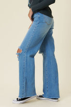 Load image into Gallery viewer, Our New Favorite Vibrant M.i.U Distressed Wide Fit Jeans featuring classic 5-pocket construction, front knee cut details, raw-edged hem, tinted wash throughout, and a zip-fly closure. These jeans are a must-have for your wardrobe this season. Pair with one of our essential bodysuits, pumps, or sneakers and a jacket for effortless style. 
