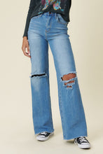 Load image into Gallery viewer, Our New Favorite Vibrant M.i.U Distressed Wide Fit Jeans featuring classic 5-pocket construction, front knee cut details, raw-edged hem, tinted wash throughout, and a zip-fly closure. These jeans are a must-have for your wardrobe this season. Pair with one of our essential bodysuits, pumps, or sneakers and a jacket for effortless style. 
