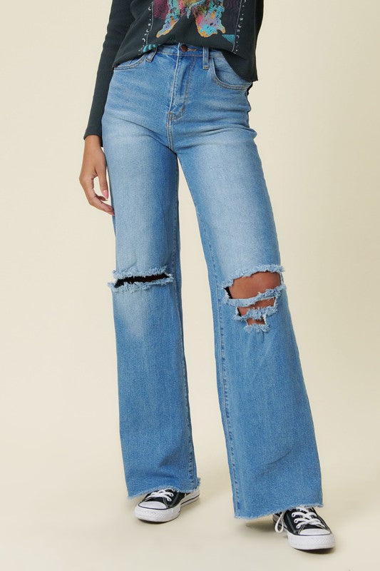 Our New Favorite Vibrant M.i.U Distressed Wide Fit Jeans featuring classic 5-pocket construction, front knee cut details, raw-edged hem, tinted wash throughout, and a zip-fly closure. These jeans are a must-have for your wardrobe this season. Pair with one of our essential bodysuits, pumps, or sneakers and a jacket for effortless style. 