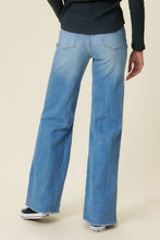 Load image into Gallery viewer, Our New Favorite Vibrant M.i.U Distressed Wide Fit Jeans featuring classic 5-pocket construction, front knee cut details, raw-edged hem, tinted wash throughout, and a zip-fly closure. These jeans are a must-have for your wardrobe this season. Pair with one of our essential bodysuits, pumps, or sneakers and a jacket for effortless style. 
