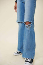 Load image into Gallery viewer, Our New Favorite Vibrant M.i.U Distressed Wide Fit Jeans featuring classic 5-pocket construction, front knee cut details, raw-edged hem, tinted wash throughout, and a zip-fly closure. These jeans are a must-have for your wardrobe this season. Pair with one of our essential bodysuits, pumps, or sneakers and a jacket for effortless style. 
