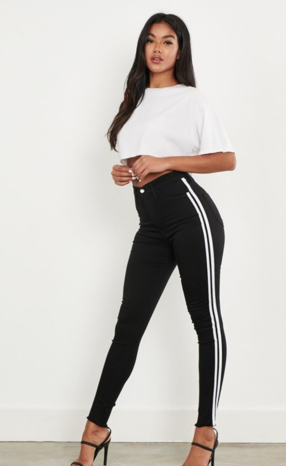 Flex your style in these cute black skinny Jeans with a contrast white stripe designs. Perfect for styling any and every way you want! These jeans come in a high rise fit featuring a raw uneven hem ends, zip and button closure. Pair with a graphic tee or chic fashion top, high heels or combat boots and of course a handbag for a complete look!