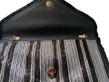 Load image into Gallery viewer, After looking high and low, traveling far and wide, our journey finally brought us to Night Life Sequin Clutch! This cute black clutch features rows of stunning black and silver sequin, and black fringe. Lift the top from the hidden magnetic closure to find a striped, lined interior with a sidewall pocket. Detachable chain strap.
