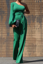Load image into Gallery viewer, One Shoulder Jumpsuit - Dark Green This jumpsuit is a statement in itself! Perfect for all of your summer fun! This green jumpsuit comes in a wide pant leg featuring a long sleeve one shoulder, adjustable tie belt, and side zipper. Pair this with a stylish heel and handbag for a complete look.
