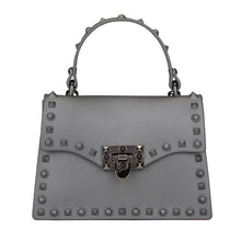 Load image into Gallery viewer, Are you ready to make a statement, babe? This rubberized trendy bag features a soft matte sage finish, studded detailing, gunmetal hardware with a locking clasp, a roomy interior compartment and also includes a crossbody strap. It&#39;s time to bring some edge and ambition to your look, sis!
